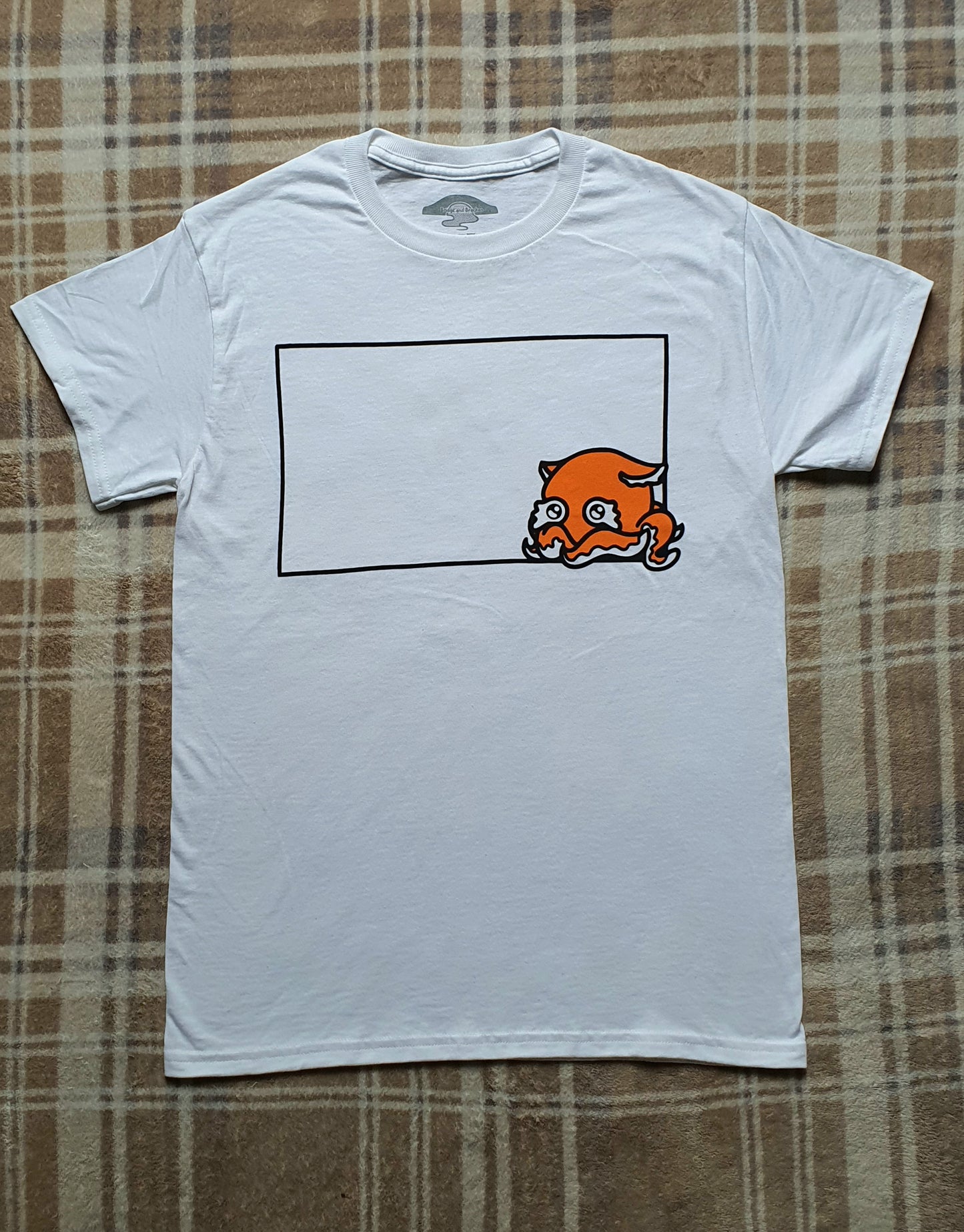 White t-shirt with a graphic design on a plaid fabric background