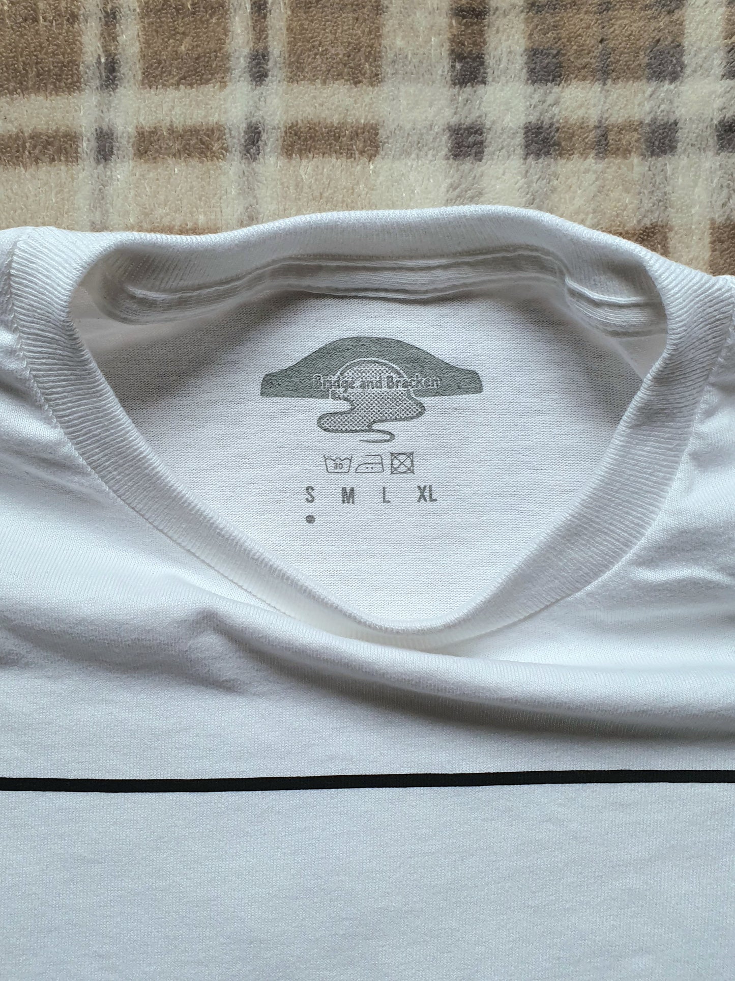 Inside neck of white t-shirt with a logo and size chart